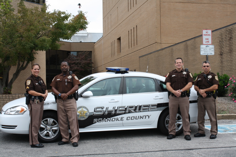 Four Sheriff Employees Standing in Front of Patrol Car
